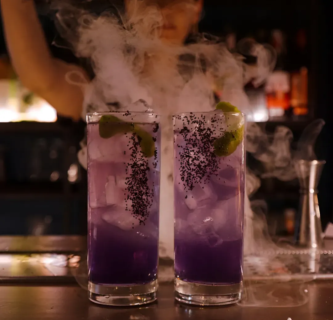 Due cocktail viola con ghiaccio, lime e fumo sullo sfondo
