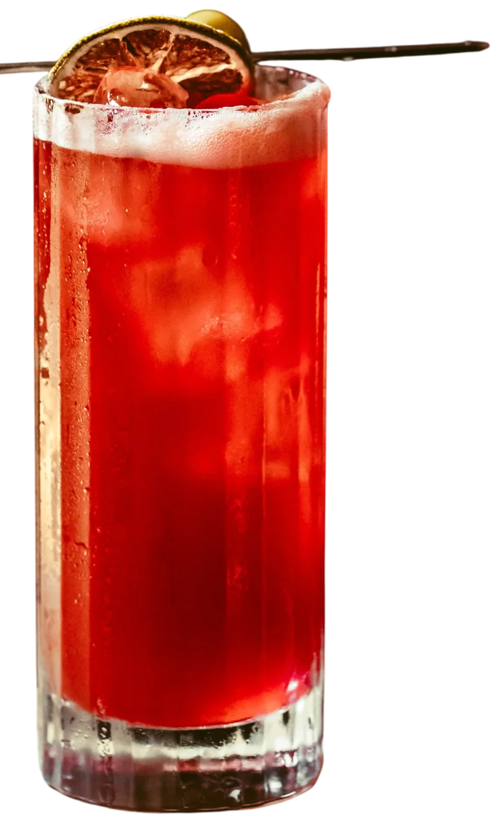 Cocktail rosso in un bicchiere rigato con fetta di lime essiccata e stick